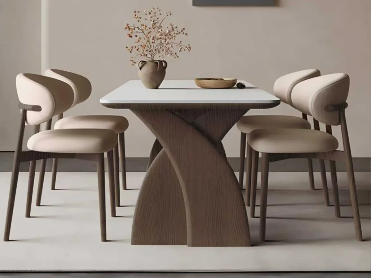 Round dining table and sculptural wooden chairs in an interior space demonstrating furniture proportions and spatial alignment.